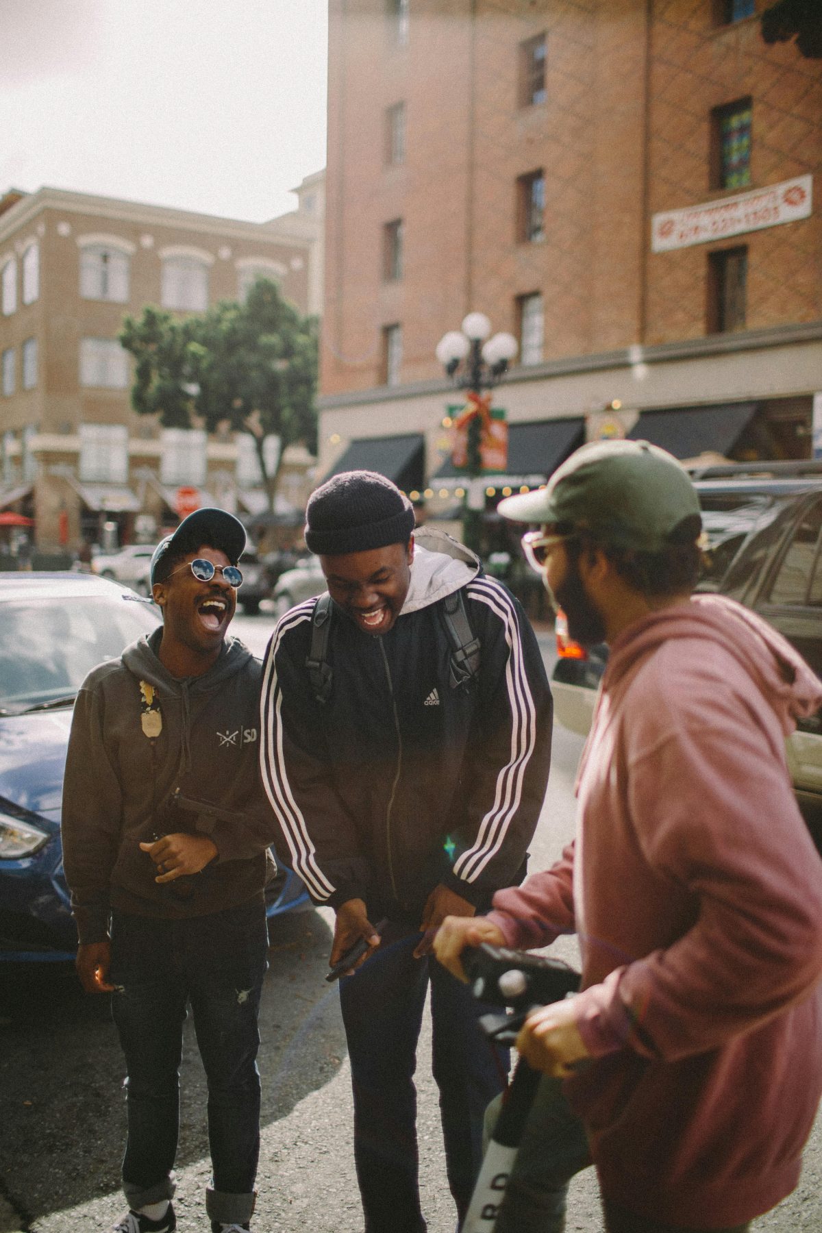 Three friends laughing together on a city street