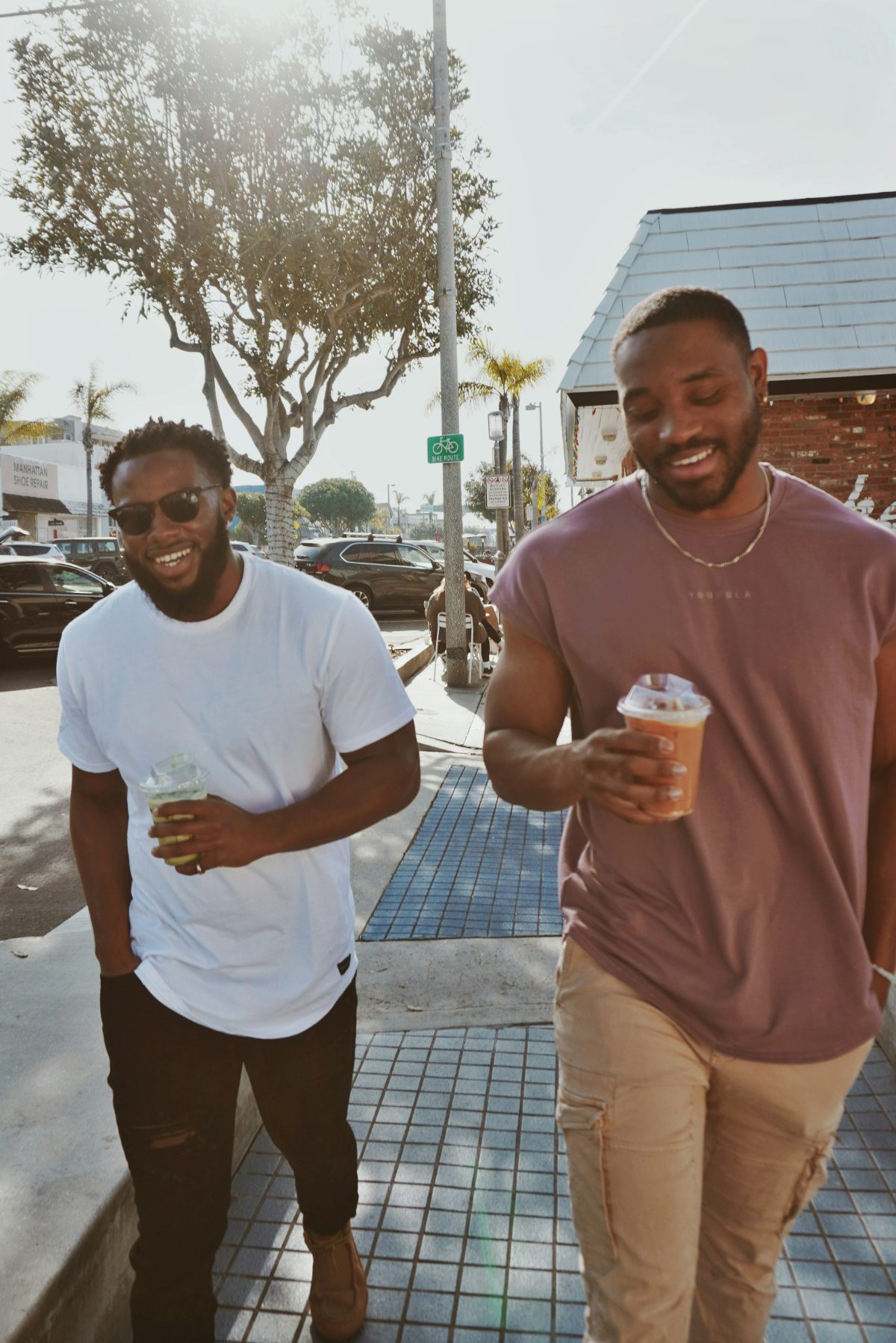 Two men walking together on a sunlit street